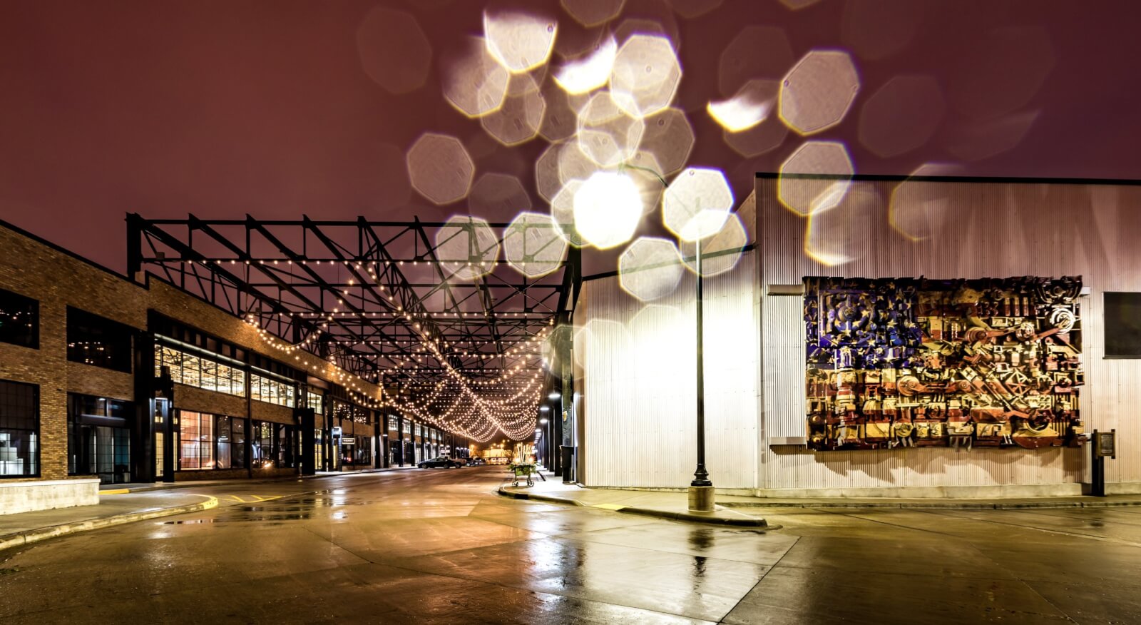 The Top 10 Places to Propose in Beloit Spine Road at night in twinkle lights overhead and an American flag artwork piece hung on a building wall.